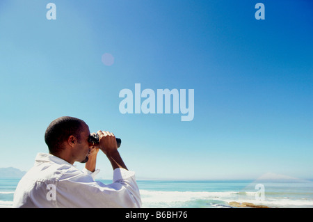 Seitenansicht des Menschen Blick durch ein Fernglas am Strand Stockfoto