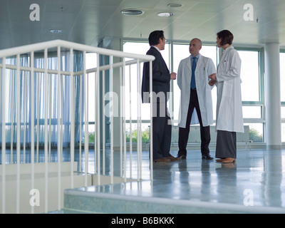 Ärzte diskutieren mit Geschäftsmann im Krankenhaus Stockfoto