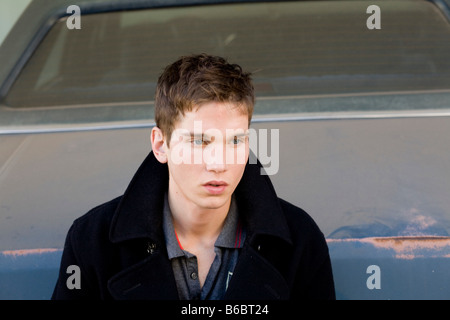 Junger Mann sitzt auf dem Auto hinten Stockfoto