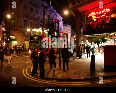 Londoner Nachtleben bunte Lichter Straßenecke mit vielen Menschen und roten Bus west end London UK Stockfoto