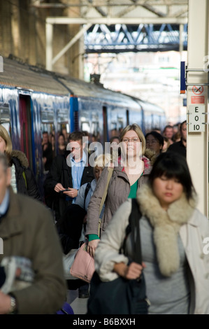 Passagiere, die aus einem Zug auf einen überfüllten Bahnhofssteig in Großbritannien steigen. Stockfoto