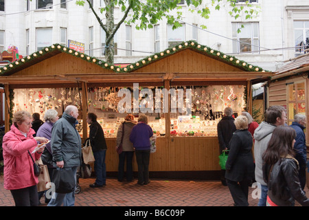 Passanten auf dem Weihnachtsmarkt Street, Birmingham mit einem Glas Christbaumkugel stand hinter Stockfoto