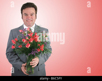 Einen schönen Mann in einem Anzug mit einem Rosenstrauß rosa Schatz über ein rosa packground Stockfoto