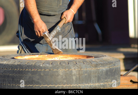 Schließen Sie herauf Bild eines Mannes hält eine Abholung während der Arbeit an einem Reifen Stockfoto