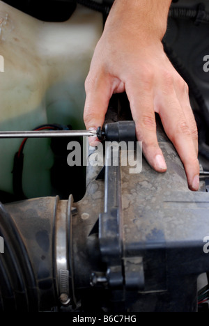Mechaniker, Drehen einer Schraube während der Befestigung eines Motors Stockfoto