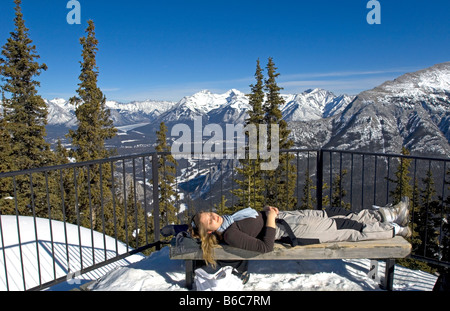 Junge Frau auf der Bank mit Blick auf Banff und das Bow Valley umgeben von den Rocky Mountains vom Gipfel des Sulphur Mountain Stockfoto