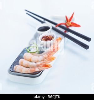 Rohe Garnelen mit Stäbchen und Sauce auf Tablett Stockfoto