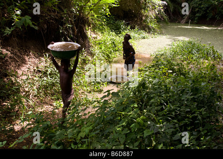 Eine junge Carring Schüssel mit schmutzigem Wasser nach Hause, Dassa, Benin, Westafrika. Stockfoto