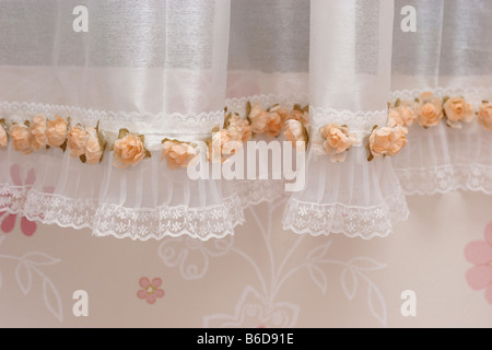 weiße Vorhänge in einem Fenster mit einer floralen Wand Stockfoto