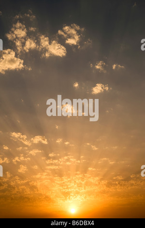 WOLKENGEBILDE HELLEN STRAHLEN DER SONNE DURCH HINTERLEUCHTETE GESCHWOLLENEN WOLKEN AM GELBEN HIMMEL Stockfoto