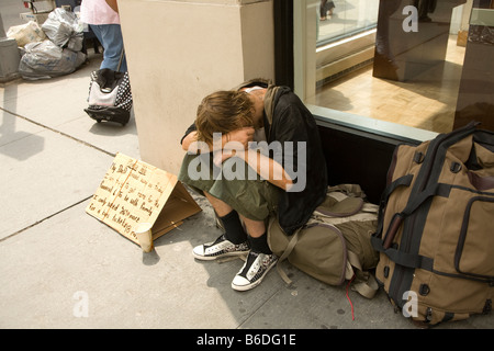 Obdachloser schläft auf dem Bürgersteig mit seinen Habseligkeiten auf der Madison Avenue in New York City Stockfoto