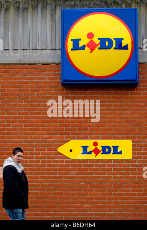 Logos und Zeichen für Lidl-Supermarkt in Kingston nach Themse, Surrey, England, mit weiblichen Passanten Stockfoto