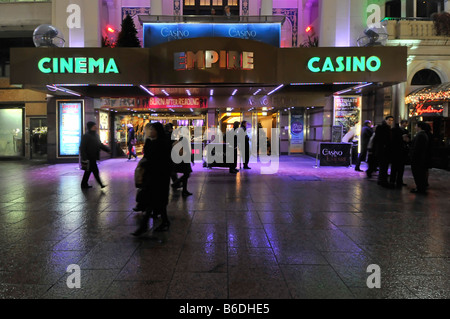 Abends Blick auf die Menschen auf dem Bürgersteig vor dem Empire Leicester Square Kino Casino Unterhaltungsgelände, in leuchtenden Farben, Flutlicht London England Großbritannien Stockfoto