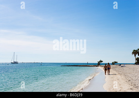 Paare, die am Strand mit einer Yacht in der Ferne, Sombrero Strand, Vaca Key, Marathon, Florida Keys Stockfoto