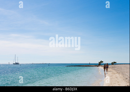 Paare, die am Strand mit einer Yacht in der Ferne, Sombrero Strand, Vaca Key, Marathon, Florida Keys Stockfoto