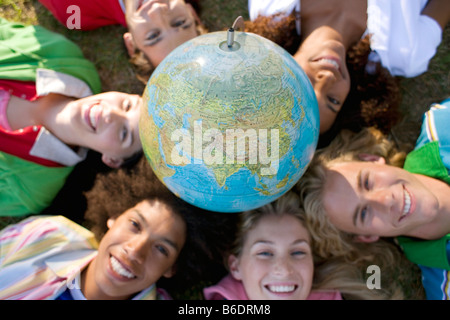 Umweltbewusstsein. Gruppe von Freunden in einem Kreis mit einem Globus der Erde ruht auf dem Kopf liegend. Stockfoto