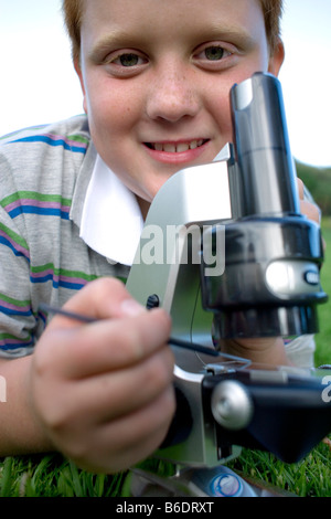 Junge mit einem Lichtmikroskop, um ein Exemplar zu studieren. Stockfoto