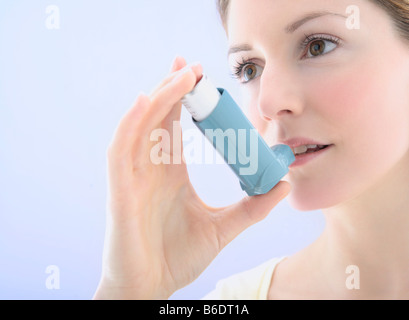 25 Jahre alte Frau, die mittels eines Inhalators um einen Asthma-Anfall zu behandeln Stockfoto