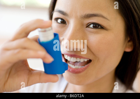 Asthma-Inhalator verwenden. Frau mit einem Inhalator, um einen Asthma-Anfall zu behandeln. Der Inhalator enthält bronchienerweiternde Medikamente. Stockfoto