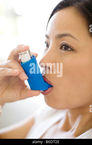 Asthma-Inhalator verwenden. Frau mit einem Inhalator, um einen Asthma-Anfall zu behandeln. Der Inhalator enthält bronchienerweiternde Medikamente. Stockfoto