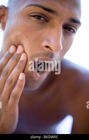 Mann, hält die Seite seines Gesichts zur Linderung der Schmerzen verursacht durch Zahnschmerzen Stockfoto