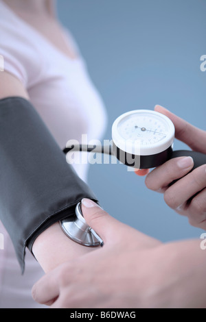 Blutdruck messen. Fünfundzwanzig Jahre alte Frau, die ihr Blut-Pressurechecked mit einem Blutdruckmessgerät. Stockfoto