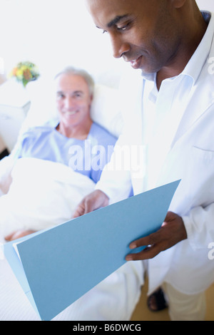 Arzt und Patient. Arzt überprüft die Krankenakte des Patienten auf einer Krankenstation. Stockfoto