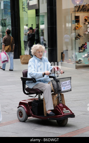 Frau eine Shopmobility Motorroller in Exeter Einkaufszentrum. Devon England UK Stockfoto