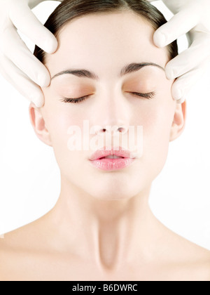 Kosmetische Chirurgie. Konzeptbild der kosmetischen Chirurgie durch ein Chirurg Hände Anheben der Haut auf das Gesicht einer Frau vertreten. Stockfoto