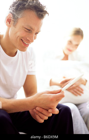 Positiven Schwangerschaftstest. Glücklicher Vater mit einem Schwangerschaftstest Stick sein, das ein positives Ergebnis anzeigt. Stockfoto