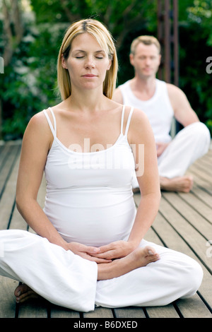 Schwangere Frau, die Durchführung von Yoga mit ihrem Ehemann Stockfoto