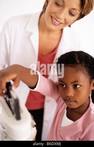 Gewichts-Check-Up. Allgemeinmedizin Arzt beobachten ihre 9 jährige Patientin die Balance auf die Waage. Stockfoto