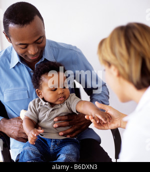 Pädiatrische Untersuchung. Arzt untersucht einen 5 Monate alten Jungen in des Vaters Schoß sitzen. Stockfoto