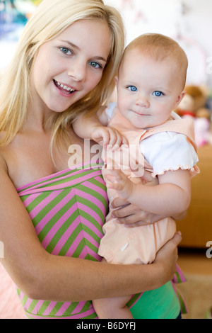 Teenager-Mutter und Baby. Junge Mutter hält ihr 10 Monate alte Tochter. Gestellt von Modellen. Stockfoto