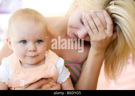 Teenager-Mutter und Baby. Junge Mutter hält ihr 10 Monate alte Tochter betonte. Gestellt von Modellen. Stockfoto