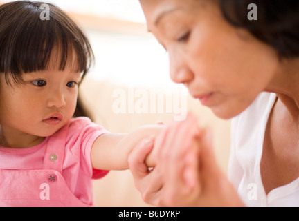 Ausschlag wird gesucht. Großmutter, die Suche nach Anzeichen für einen Ausschlag auf ihre Enkelin Arm und Hand. Stockfoto