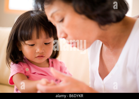 Ausschlag wird gesucht. Großmutter, die Suche nach Anzeichen für einen Ausschlag auf ihre Enkelin Arm und Hand. Stockfoto