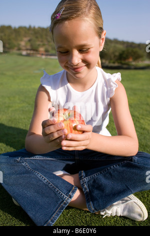 Mädchen hält einen Apfel. Diese Frucht ist eine gute Quelle für Vitamin C. Frucht ist auch eine gute Quelle für Mineralstoffe und Ballaststoffe. Stockfoto