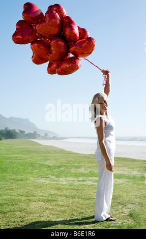 Frau hält herzförmige Luftballons. Stockfoto