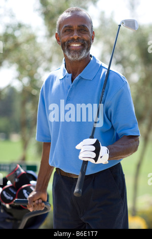Golf-Spieler. Mann hält einen Golfclub und seine Golf-Bag auf einem Wagen ziehen. Stockfoto