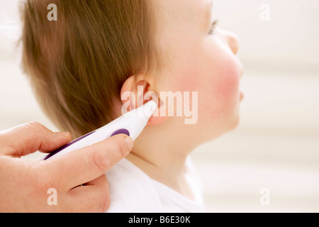 Temperaturmessung. Motherusing ein digitales Thermometer um ihre Babys auf Temperatur zu messen. Stockfoto