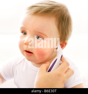 Temperaturmessung. Motherusing ein digitales Thermometer um ihre Babys auf Temperatur zu messen. Stockfoto