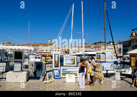 Touristen zu Fuß entlang des Piers, wo Maler setzen ihre Arbeit im Hafen von SAint Tropez Stockfoto