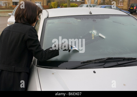 Frau Person kratzen Eis aus einem Autofenster Windschutzscheibe an einem frostigen Morgen Stockfoto