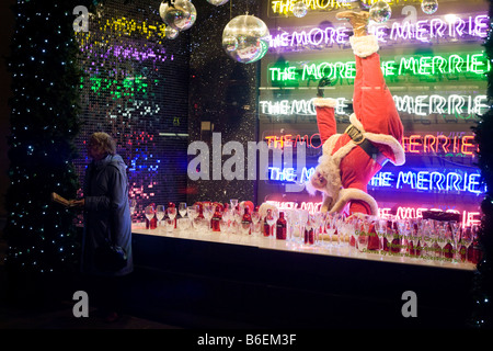 Eine Weihnachts-Shopper hält in der Nähe ein Weihnachtsmann in einem saisonalen Fenster des Kaufhauses Selfridges in der Oxford Street Stockfoto