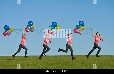 Ein Bild der Sequenz ein junges Mädchen (11) laufen glücklich über grünen Rasen mit einem Bündel von Ballons hinter und blauer Himmel. Stockfoto