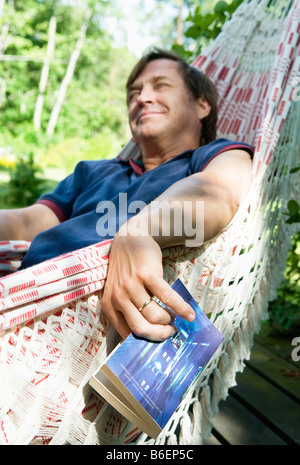 Mann mit Buch in der Hängematte Stockfoto