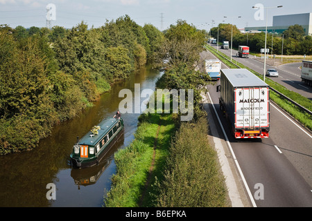 Hohen Verkehrsaufkommens auf der A38 kontrastiert mit einem Narrowboat gemächlich seinen Weg entlang der Trent und Mersey Kanal in der Nähe von Burton. Stockfoto