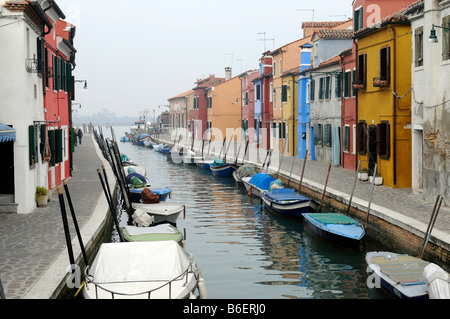Kanal ist gesäumt von Boote laufen zwischen den bunt bemalten Häuserfassaden in Burano, Venedig, Venetien, Italien, Europa Stockfoto
