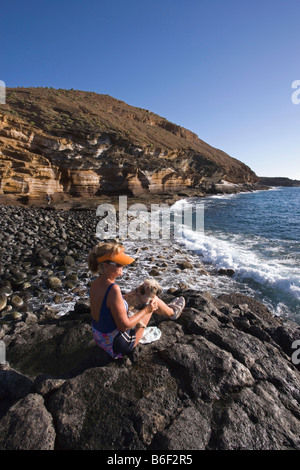 Spanien Kanaren Teneriffa Costa del Silencio Senior. Frau und Hund am Meer genießen Stockfoto